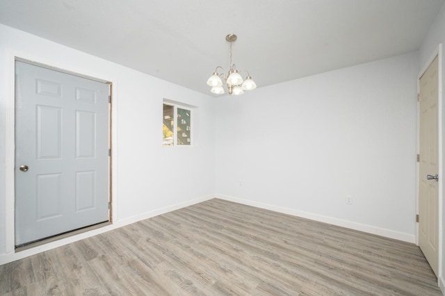 empty room featuring an inviting chandelier and hardwood / wood-style floors