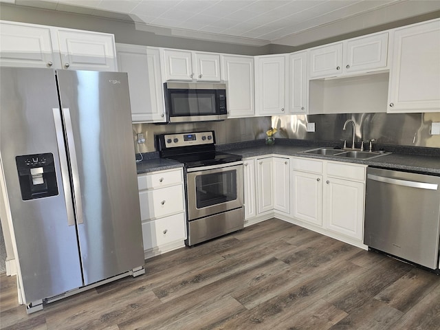 kitchen with sink, dark wood-type flooring, decorative backsplash, white cabinets, and appliances with stainless steel finishes