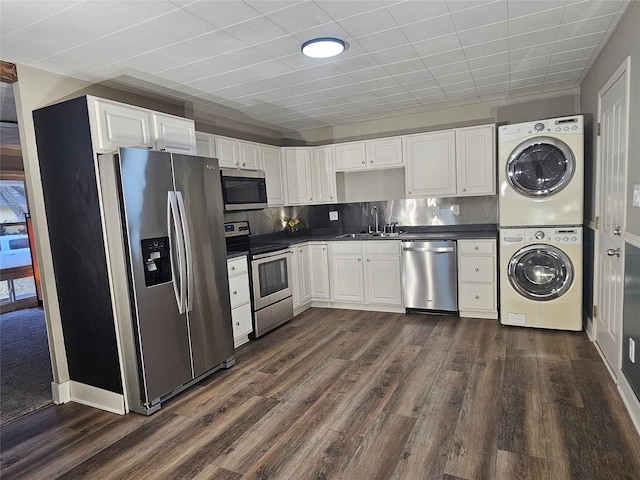 kitchen with appliances with stainless steel finishes, tasteful backsplash, white cabinets, dark hardwood / wood-style floors, and stacked washer / drying machine