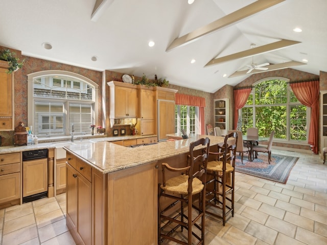 kitchen featuring a spacious island, vaulted ceiling with beams, light stone countertops, a kitchen bar, and ceiling fan