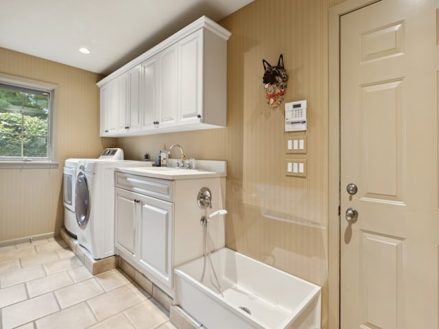 clothes washing area featuring sink, washing machine and dryer, light tile patterned floors, and cabinets