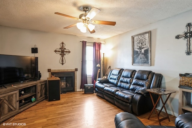 living room with a textured ceiling, wood-type flooring, and ceiling fan