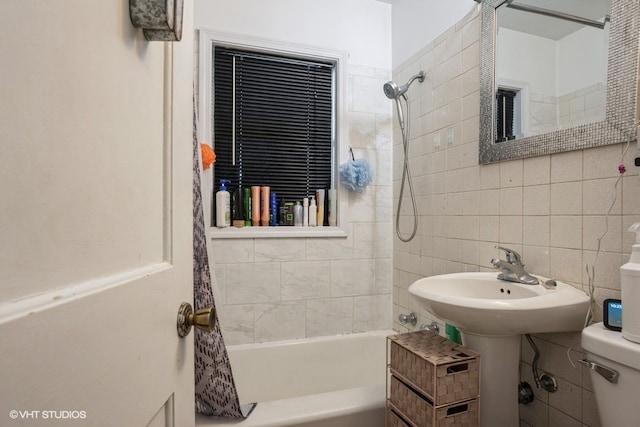 bathroom with toilet, tasteful backsplash, shower / bathtub combination with curtain, and tile walls