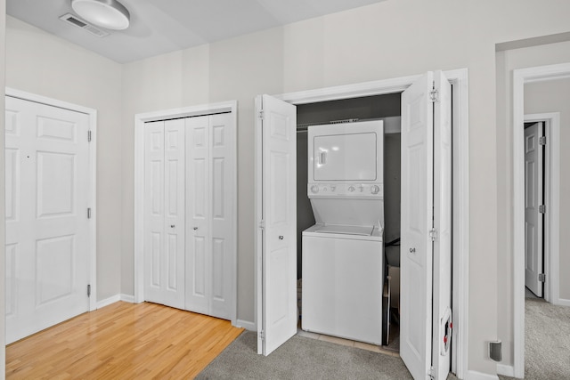 washroom with stacked washer and clothes dryer and hardwood / wood-style flooring