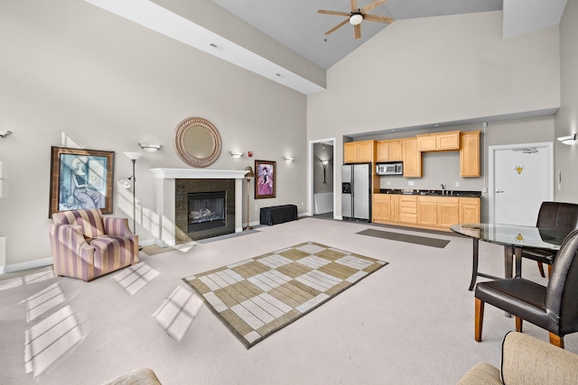 carpeted living room featuring sink, high vaulted ceiling, and ceiling fan