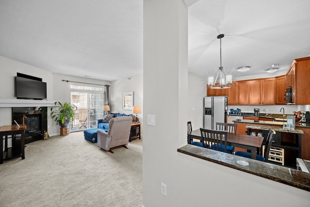 living room with light carpet, an inviting chandelier, a high end fireplace, and sink