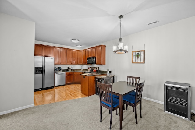 kitchen featuring heating unit, appliances with stainless steel finishes, pendant lighting, a notable chandelier, and light colored carpet