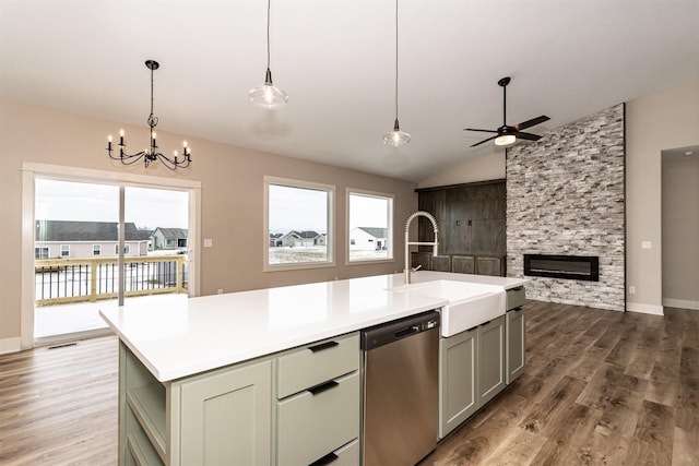 kitchen with pendant lighting, stainless steel dishwasher, a stone fireplace, and an island with sink