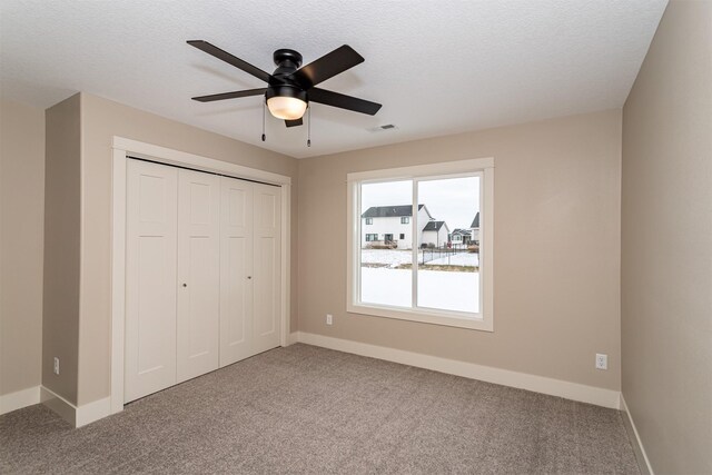 unfurnished bedroom with ceiling fan, a closet, carpet floors, and a textured ceiling