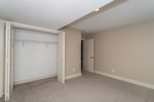 unfurnished bedroom with a textured ceiling, a closet, and light carpet