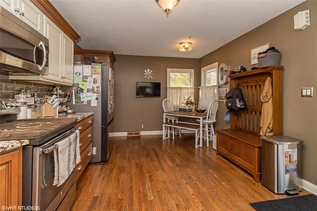 kitchen featuring white cabinetry, appliances with stainless steel finishes, dark hardwood / wood-style flooring, and decorative backsplash