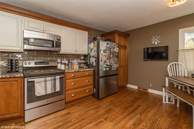 kitchen with white cabinetry, backsplash, stainless steel appliances, and dark wood-type flooring