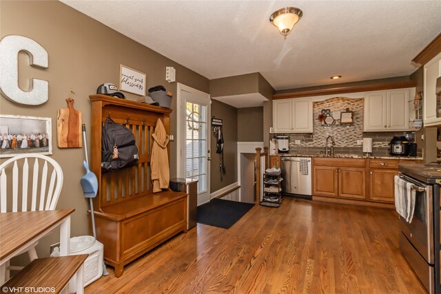 kitchen with white cabinets, tasteful backsplash, appliances with stainless steel finishes, light wood-type flooring, and sink