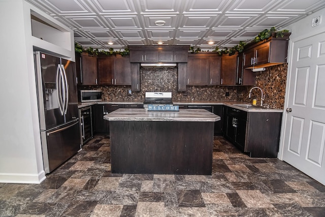 kitchen featuring light stone countertops, dark brown cabinetry, stainless steel appliances, sink, and a kitchen island