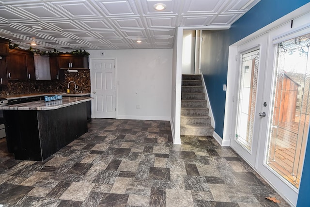 kitchen with electric range oven, a kitchen breakfast bar, decorative backsplash, dark brown cabinets, and a kitchen island