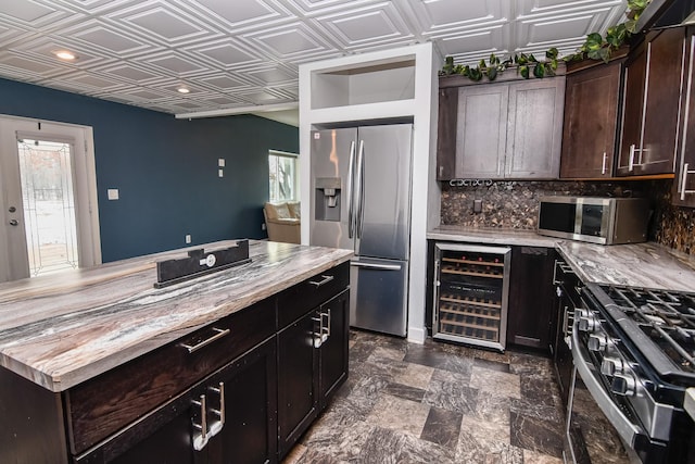 kitchen with dark brown cabinetry, wooden counters, beverage cooler, and stainless steel appliances