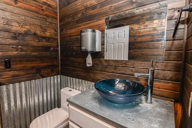 bathroom with vanity, toilet, and wood walls