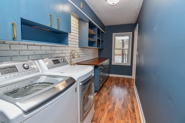 laundry area featuring dark hardwood / wood-style floors, washer and clothes dryer, cabinets, and a textured ceiling