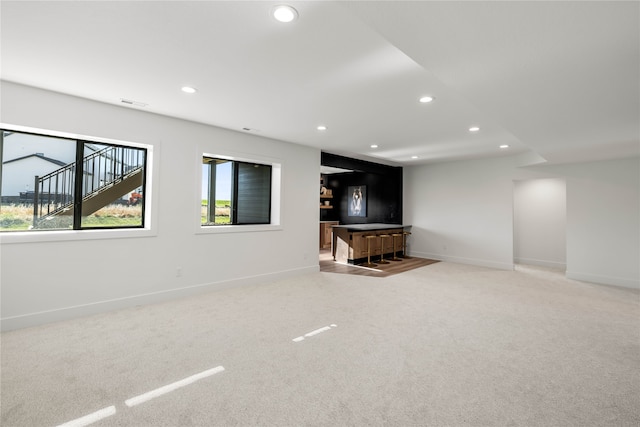 unfurnished living room with carpet floors and bar area