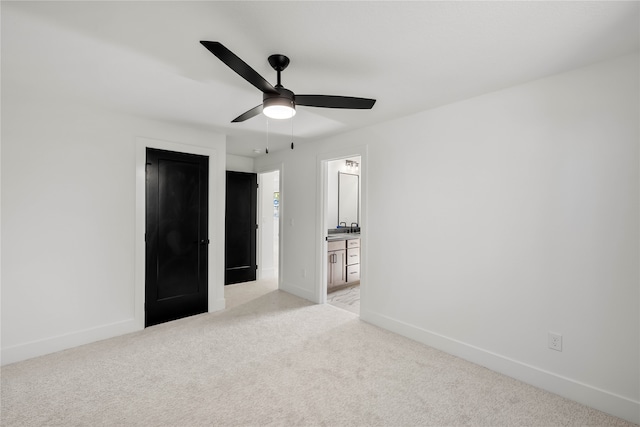 unfurnished bedroom featuring light colored carpet, ceiling fan, and ensuite bath