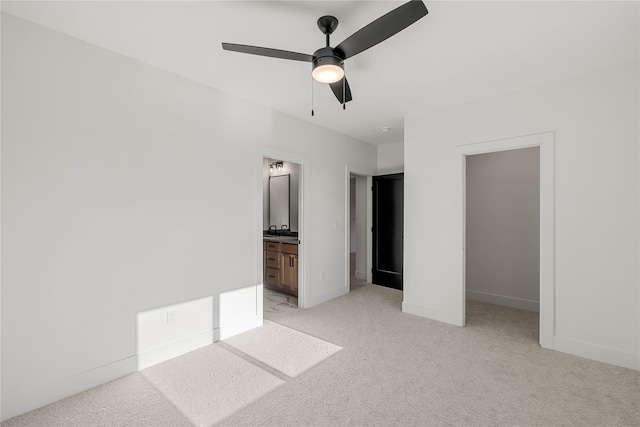 unfurnished bedroom featuring a closet, ensuite bath, light carpet, and ceiling fan