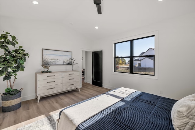 bedroom featuring light hardwood / wood-style floors, vaulted ceiling, and ceiling fan