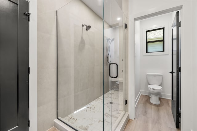 bathroom featuring a shower with shower door, wood-type flooring, and toilet