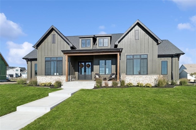 1517 SW Des Moines St, Ankeny, IA 50023 - back of house featuring board and batten siding, stone siding, a shingled roof, a lawn, and french doors