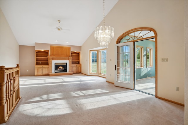 unfurnished living room with ceiling fan with notable chandelier, high vaulted ceiling, built in features, and light colored carpet