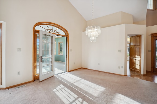 empty room featuring a chandelier, light carpet, and high vaulted ceiling