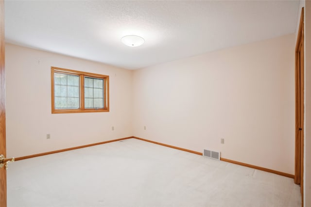 spare room with a textured ceiling and light colored carpet