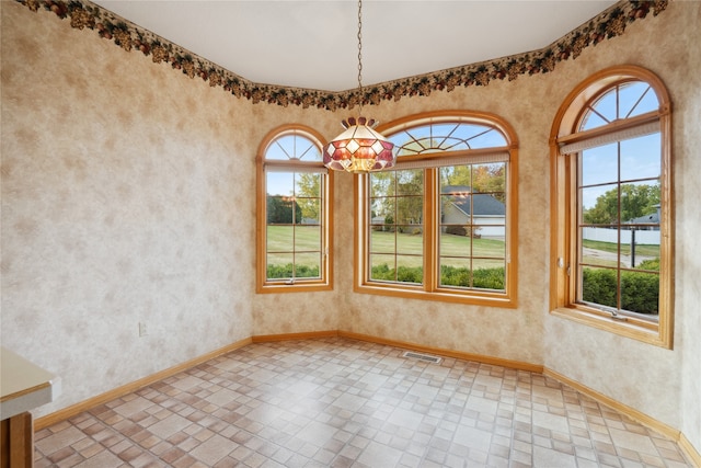 empty room with a chandelier and plenty of natural light