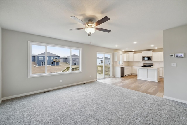 unfurnished living room with light carpet, a ceiling fan, visible vents, and baseboards