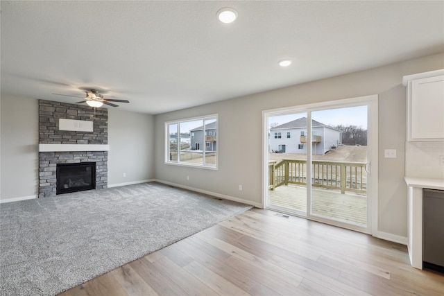 unfurnished living room with light wood-style flooring, visible vents, baseboards, and a stone fireplace