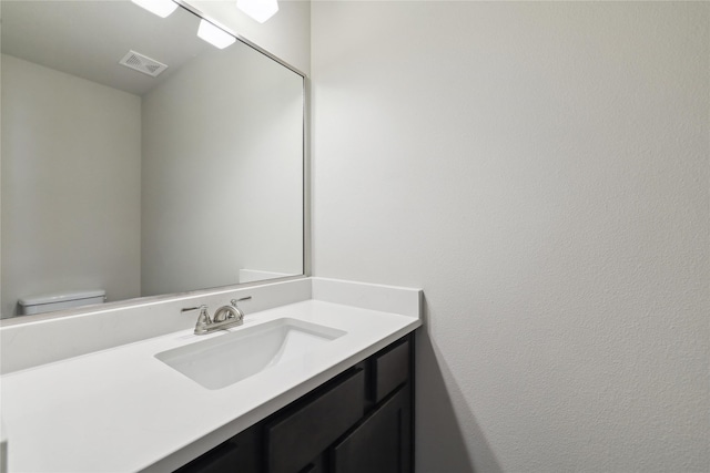 half bathroom featuring toilet, visible vents, and vanity