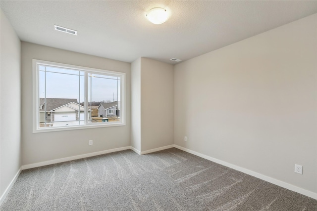 empty room featuring a textured ceiling, carpet floors, visible vents, and baseboards