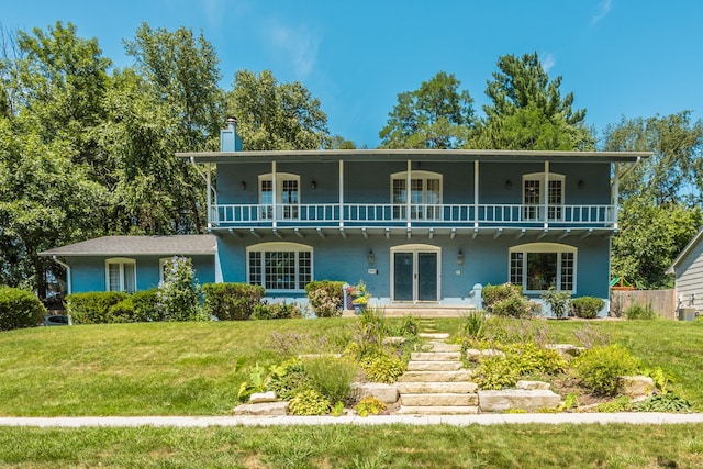 rear view of house featuring a yard and a balcony