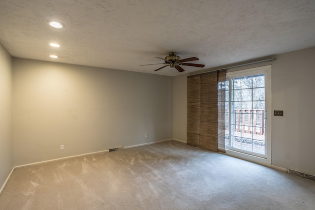 carpeted empty room featuring ceiling fan and a textured ceiling