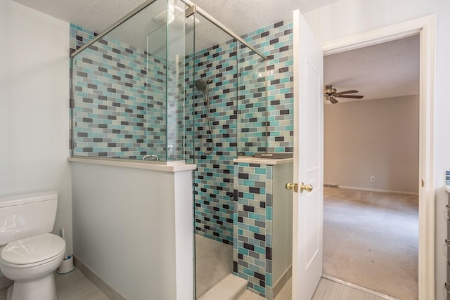 bathroom featuring ceiling fan, toilet, a textured ceiling, and a shower