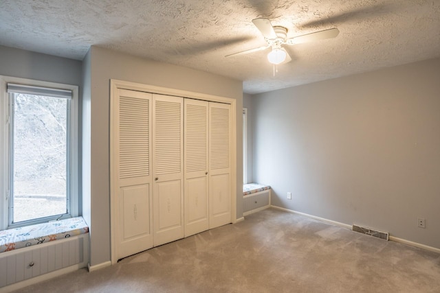 unfurnished bedroom featuring ceiling fan, a closet, carpet flooring, and multiple windows