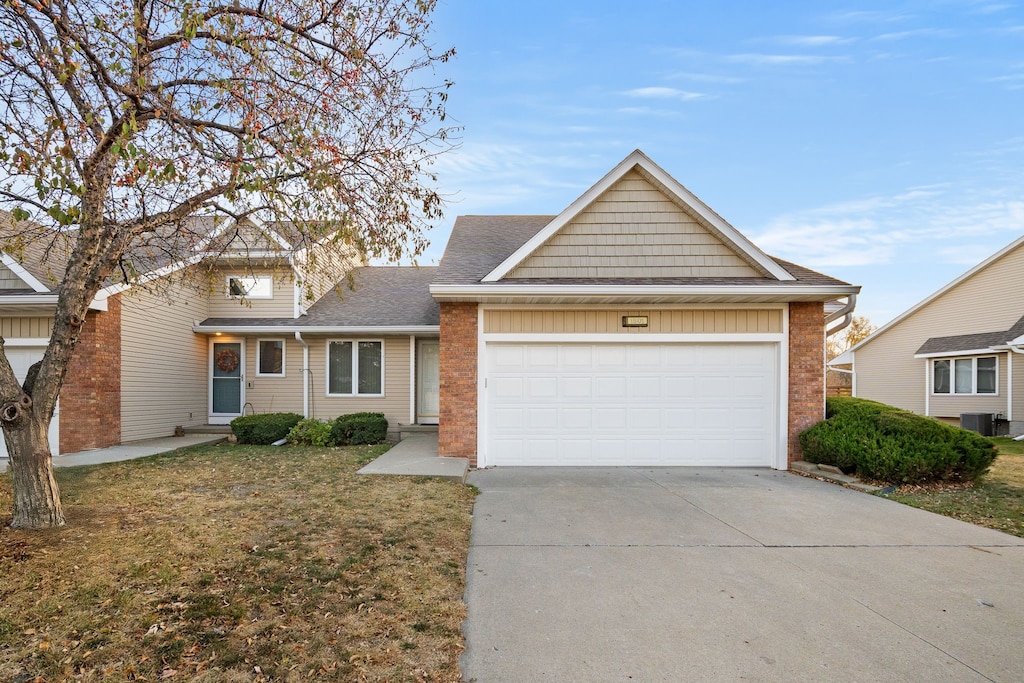 view of front of property with a front yard, central AC unit, and a garage