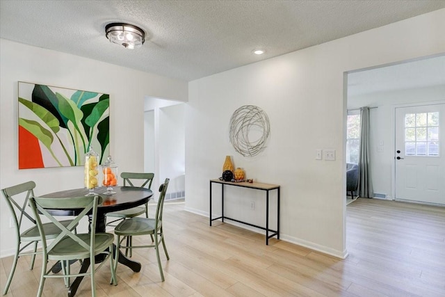 dining space featuring recessed lighting, baseboards, light wood-type flooring, and a textured ceiling