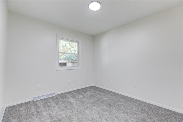 empty room with baseboards, visible vents, and carpet