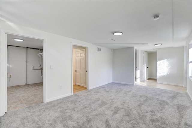 unfurnished bedroom featuring carpet flooring, baseboards, visible vents, and a walk in closet