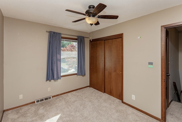 unfurnished bedroom with light carpet, a closet, and ceiling fan