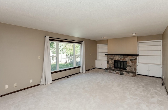 unfurnished living room with light colored carpet, a textured ceiling, built in features, and a fireplace