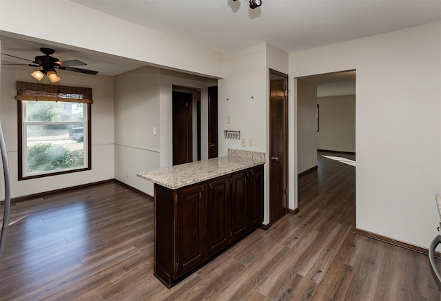 kitchen featuring ceiling fan, dark brown cabinetry, light stone countertops, dark wood-type flooring, and a textured ceiling