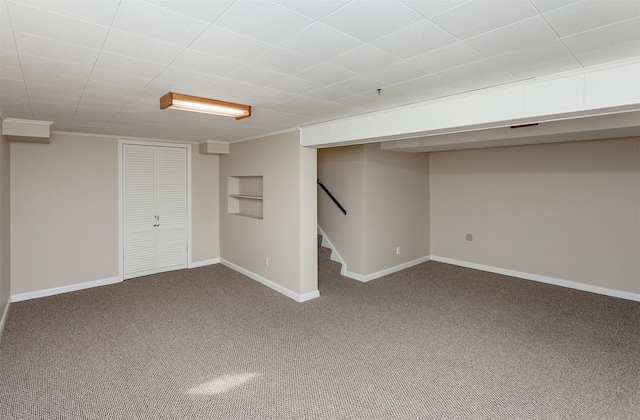 basement featuring carpet, built in shelves, and crown molding