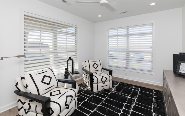 living area featuring dark hardwood / wood-style floors, ceiling fan, and a healthy amount of sunlight