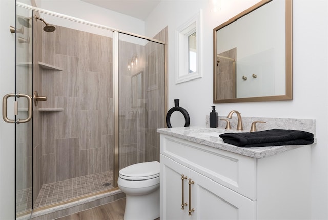 bathroom featuring vanity, hardwood / wood-style flooring, toilet, and a shower with door